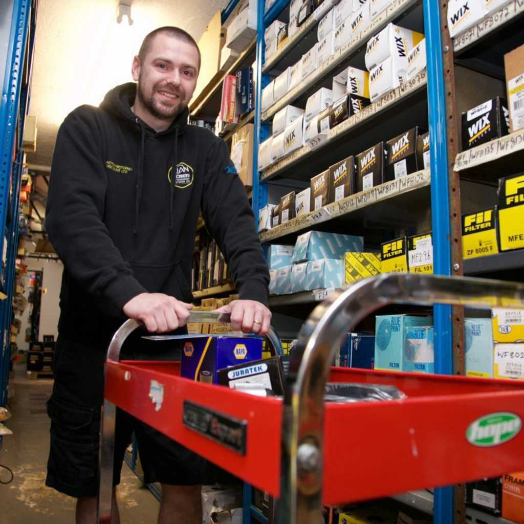 Male staff member pushing a cart filled with products